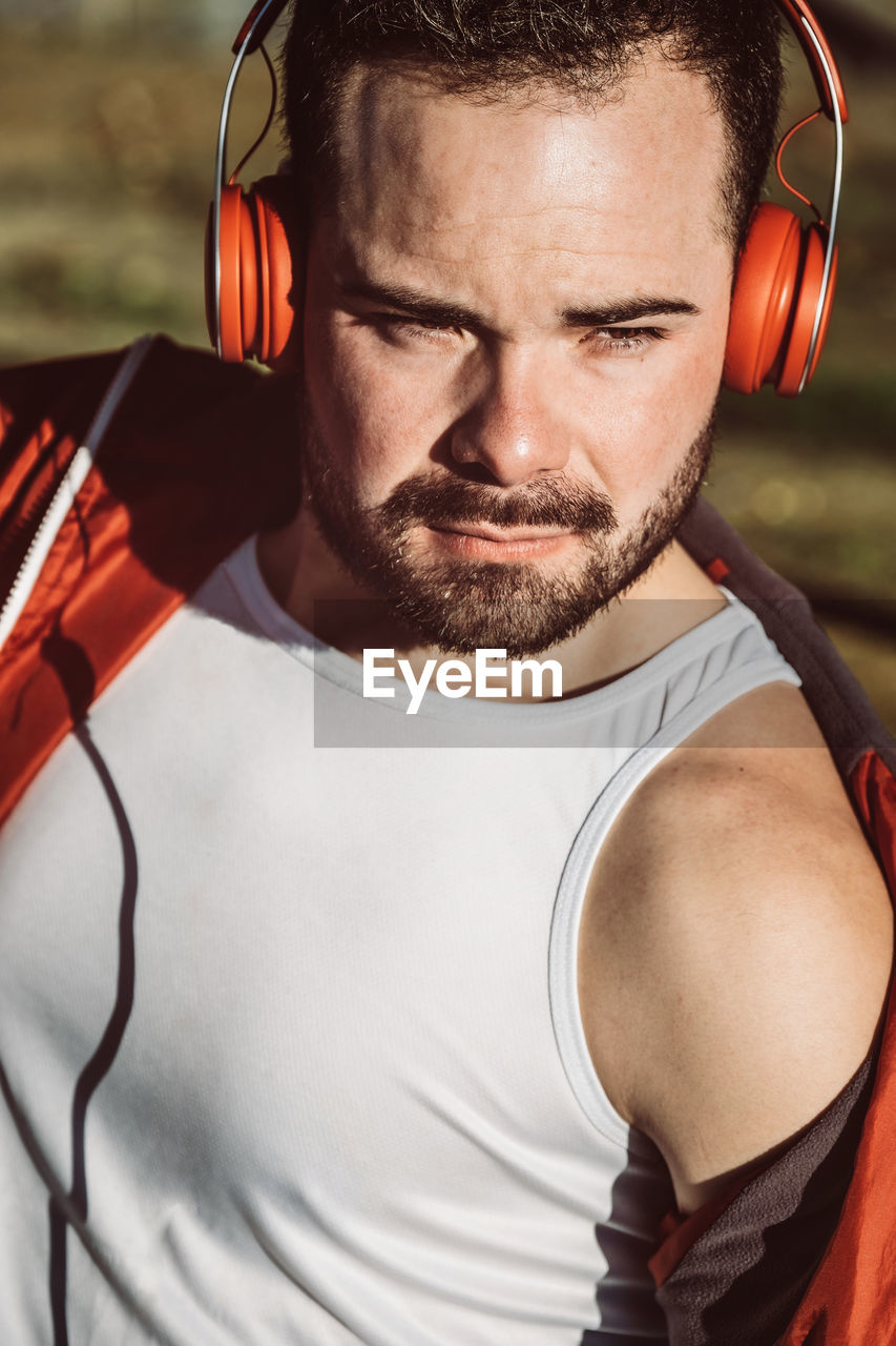 Close-up of young man wearing headphones looking away outdoors