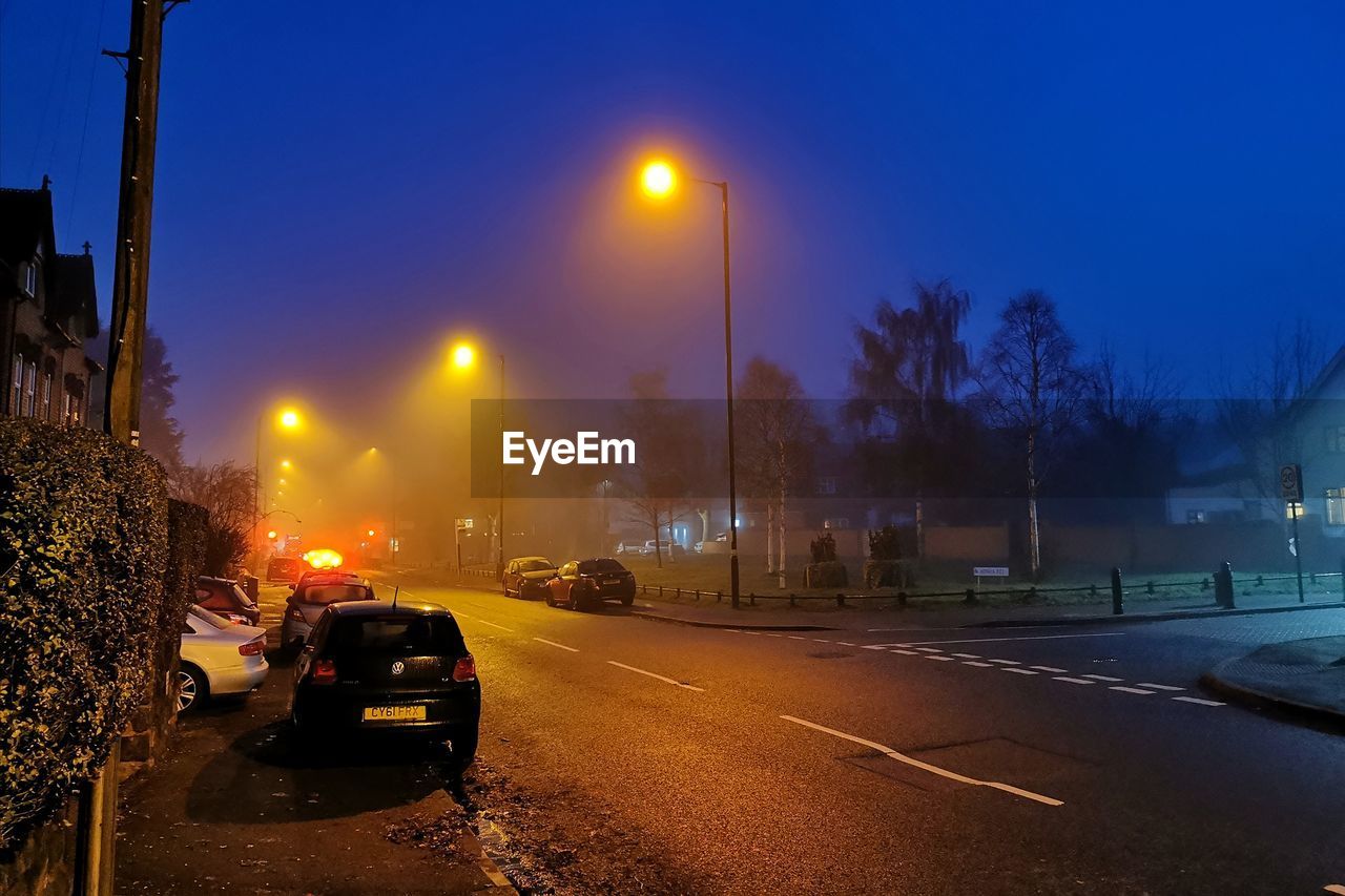 CARS ON ILLUMINATED ROAD AT NIGHT