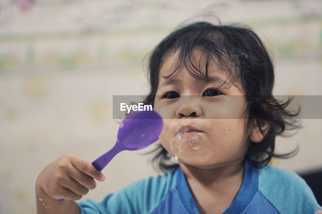 Close-up of cute girl eating food while holding spoon