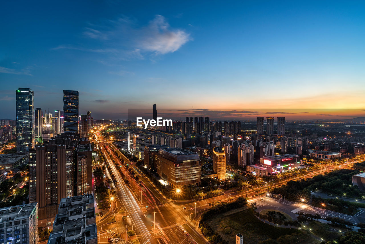 Illuminated cityscape against sky during sunset