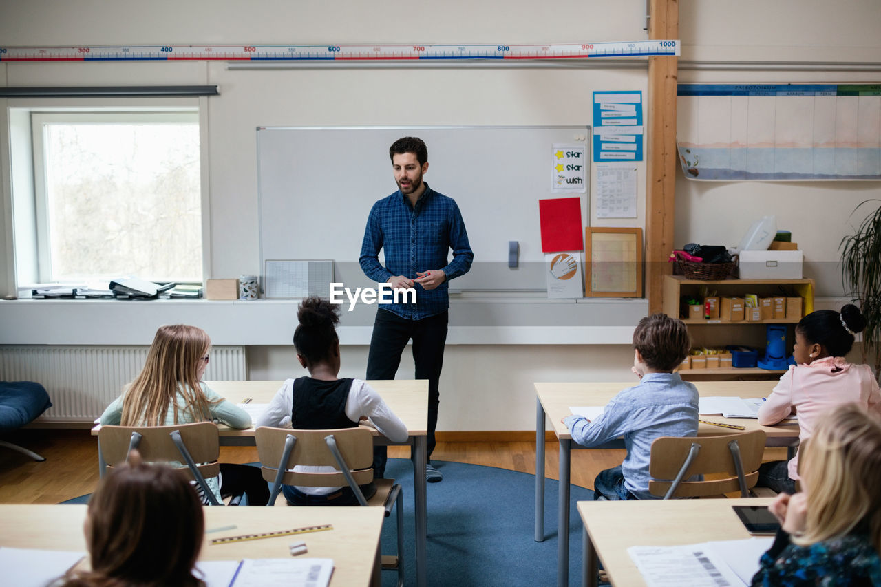 Confident teacher explaining students in classroom at school