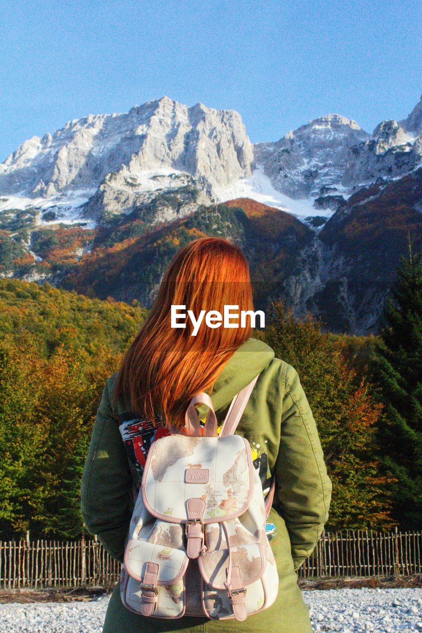 Rear view of woman with backpack looking at mountains