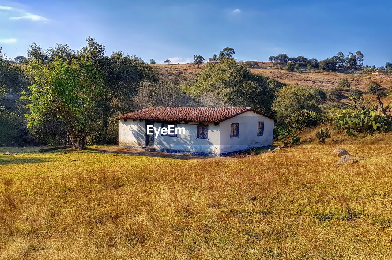 HOUSE ON FIELD AGAINST SKY