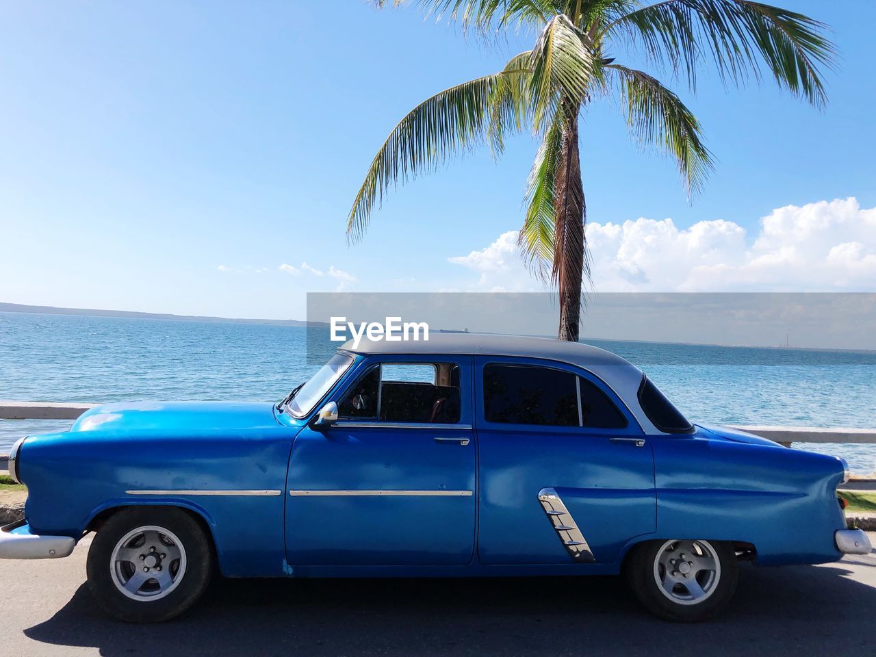 Vintage car on beach against blue sky