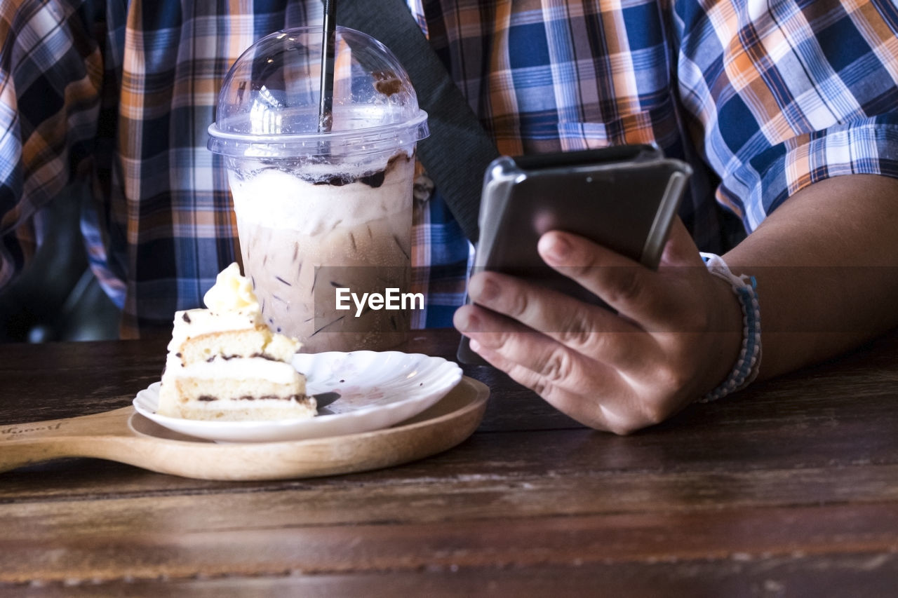 CLOSE-UP OF HAND HOLDING ICE CREAM WITH TABLE