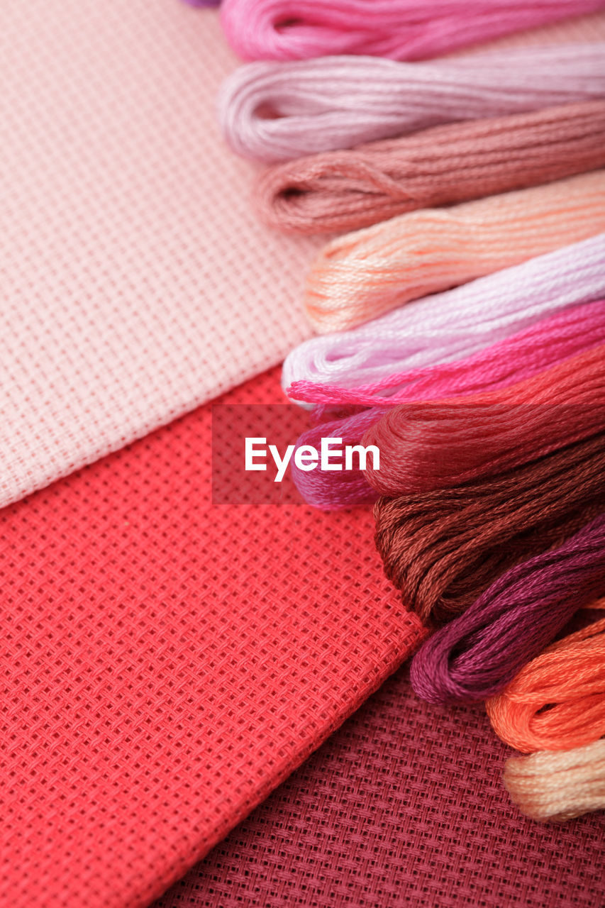 CLOSE-UP OF WOMAN LYING ON MULTI COLORED PINK FABRIC