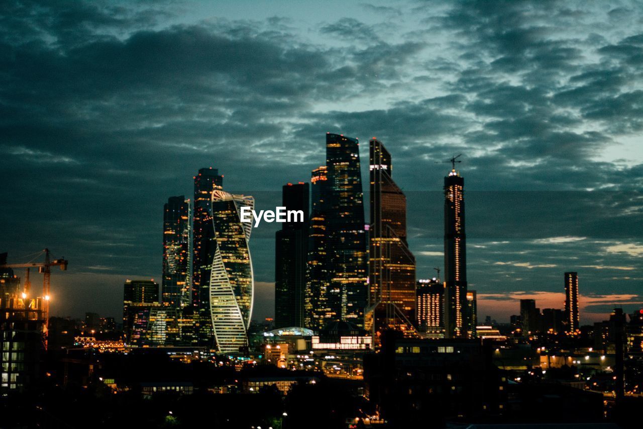 ILLUMINATED MODERN BUILDINGS AGAINST SKY AT DUSK