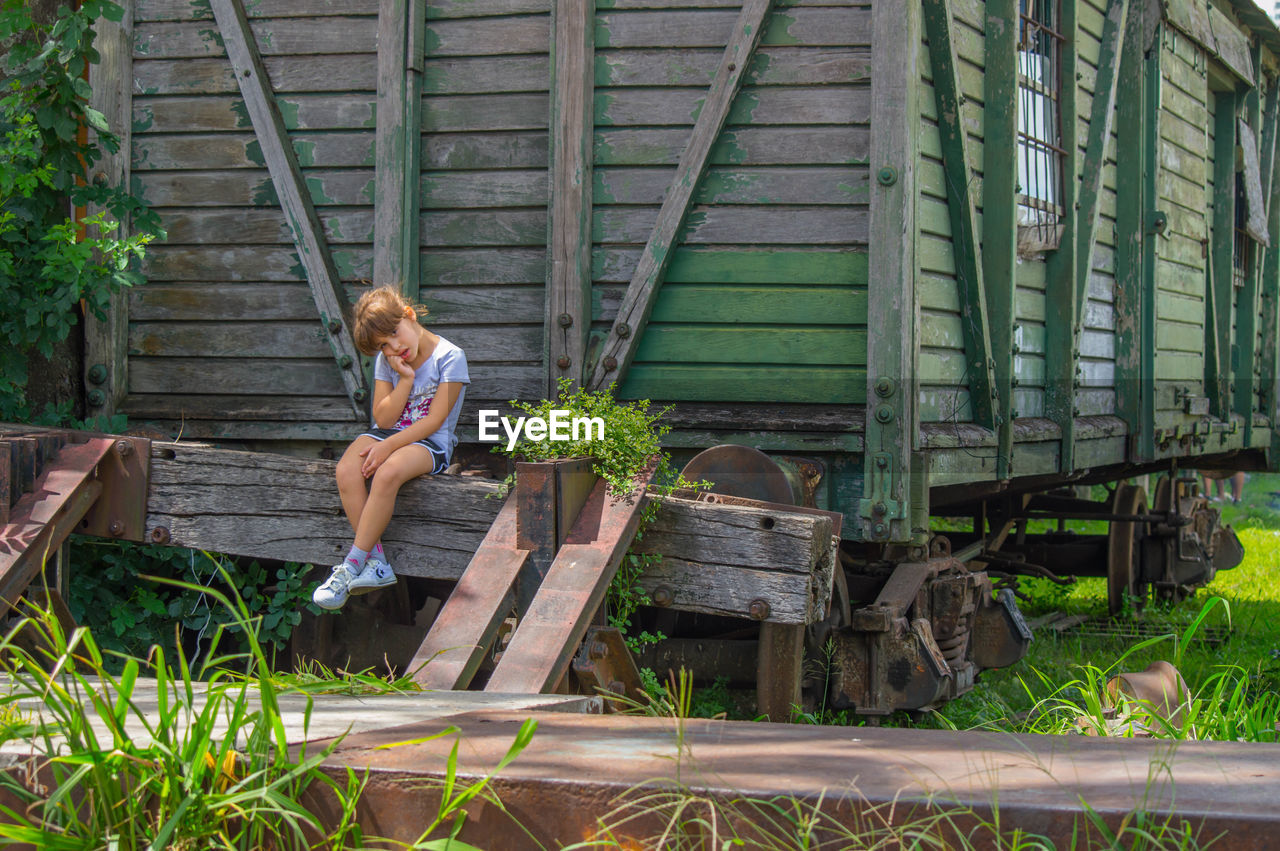 Little blonde girl posing in front of old train wagon