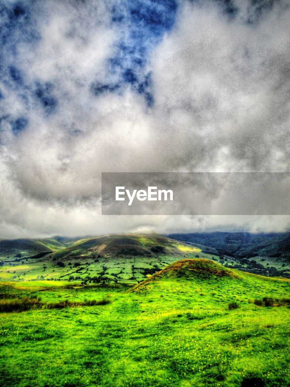 Scenic view of grassy hills against cloudy sky
