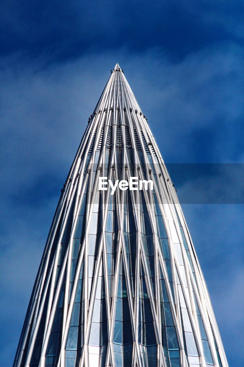 LOW ANGLE VIEW OF MODERN GLASS BUILDING AGAINST BLUE SKY