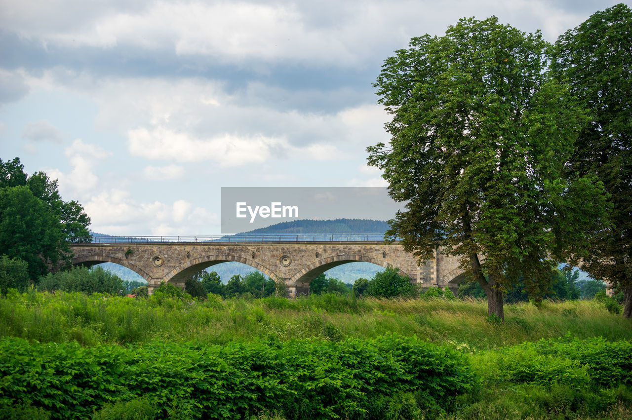 Arch bridge and trees against sky