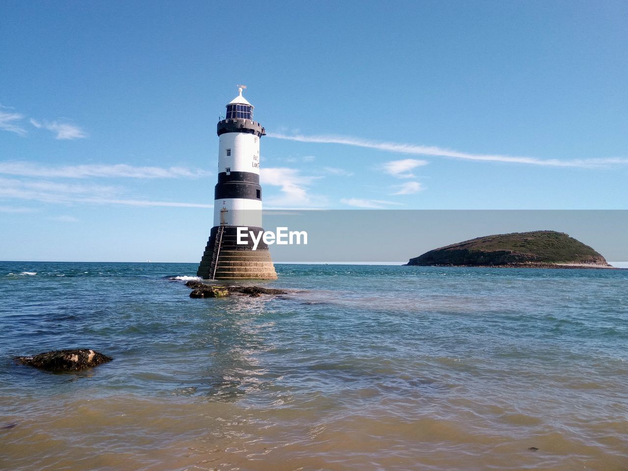 Lighthouse by sea against sky