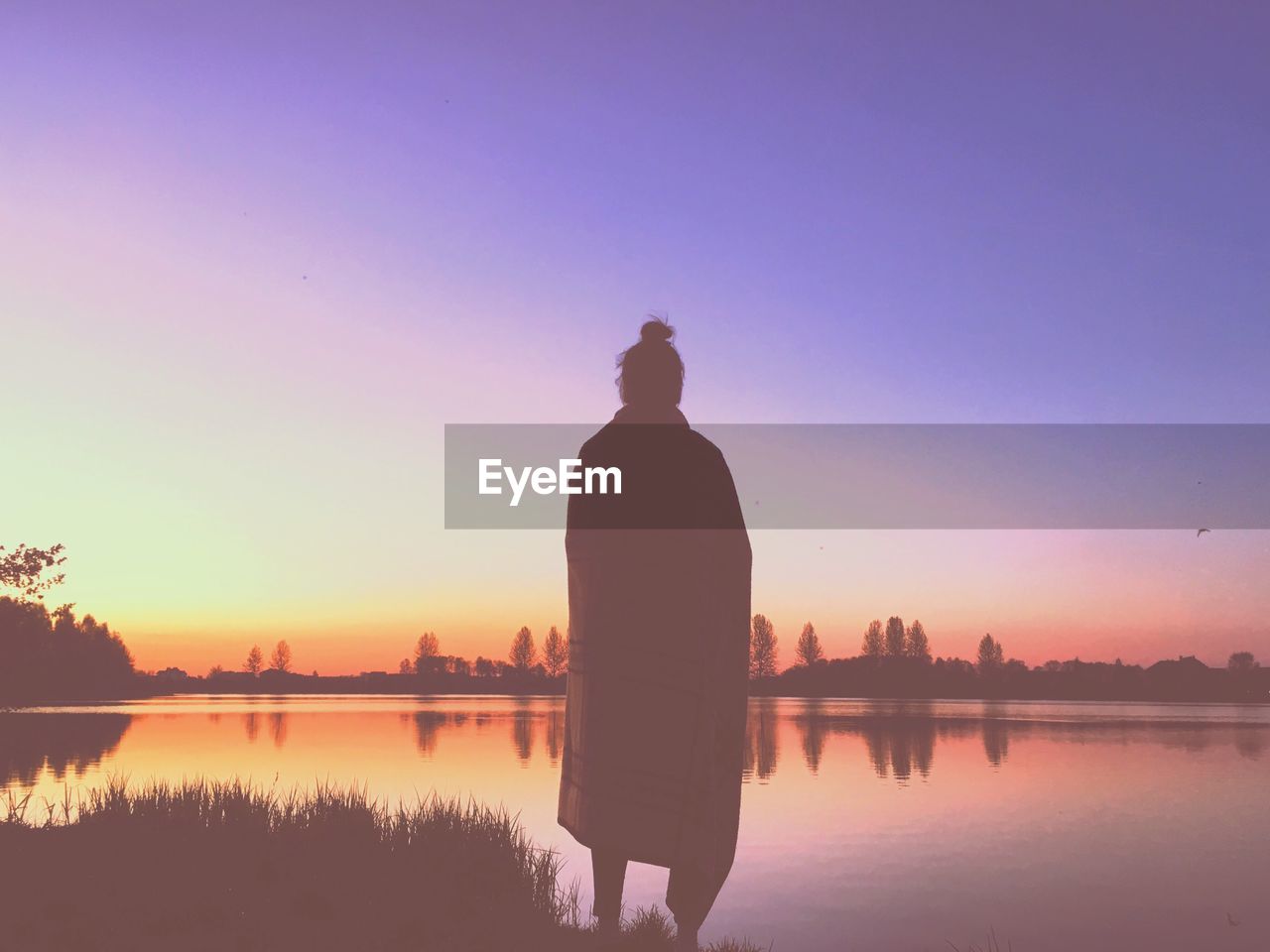 SILHOUETTE MAN STANDING BY LAKE AGAINST SKY DURING SUNSET