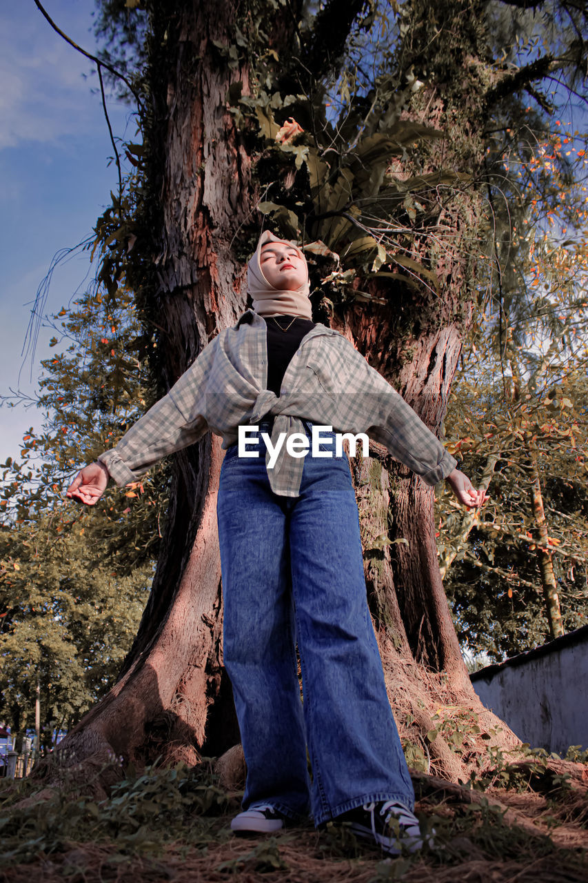 Portrait of women standing by tree trunk in forest