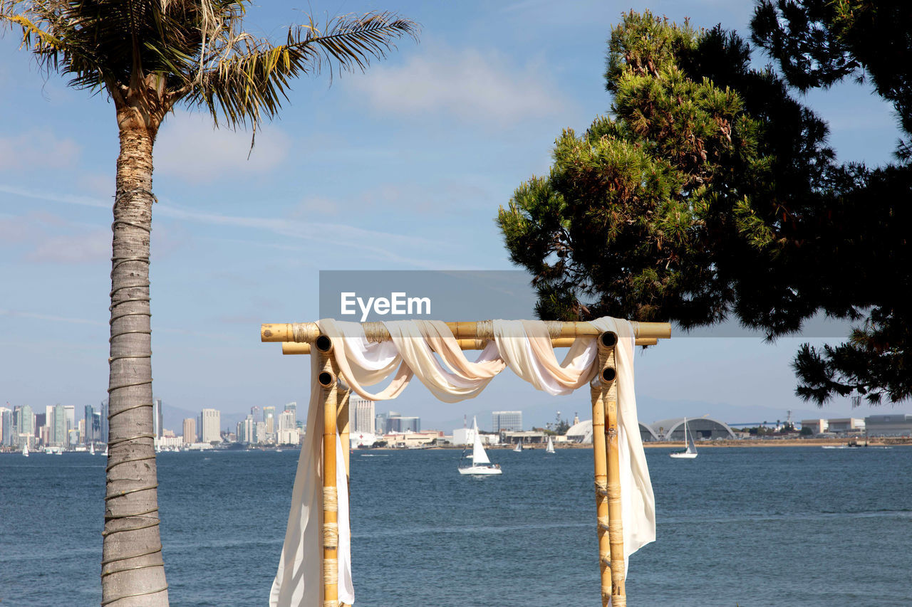 Square wooden wedding arch for outdoor beach yacht club wedding. white chairs and decorated arch 