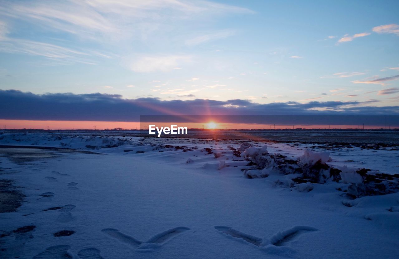 Scenic view of snowcapped landscape at sunset