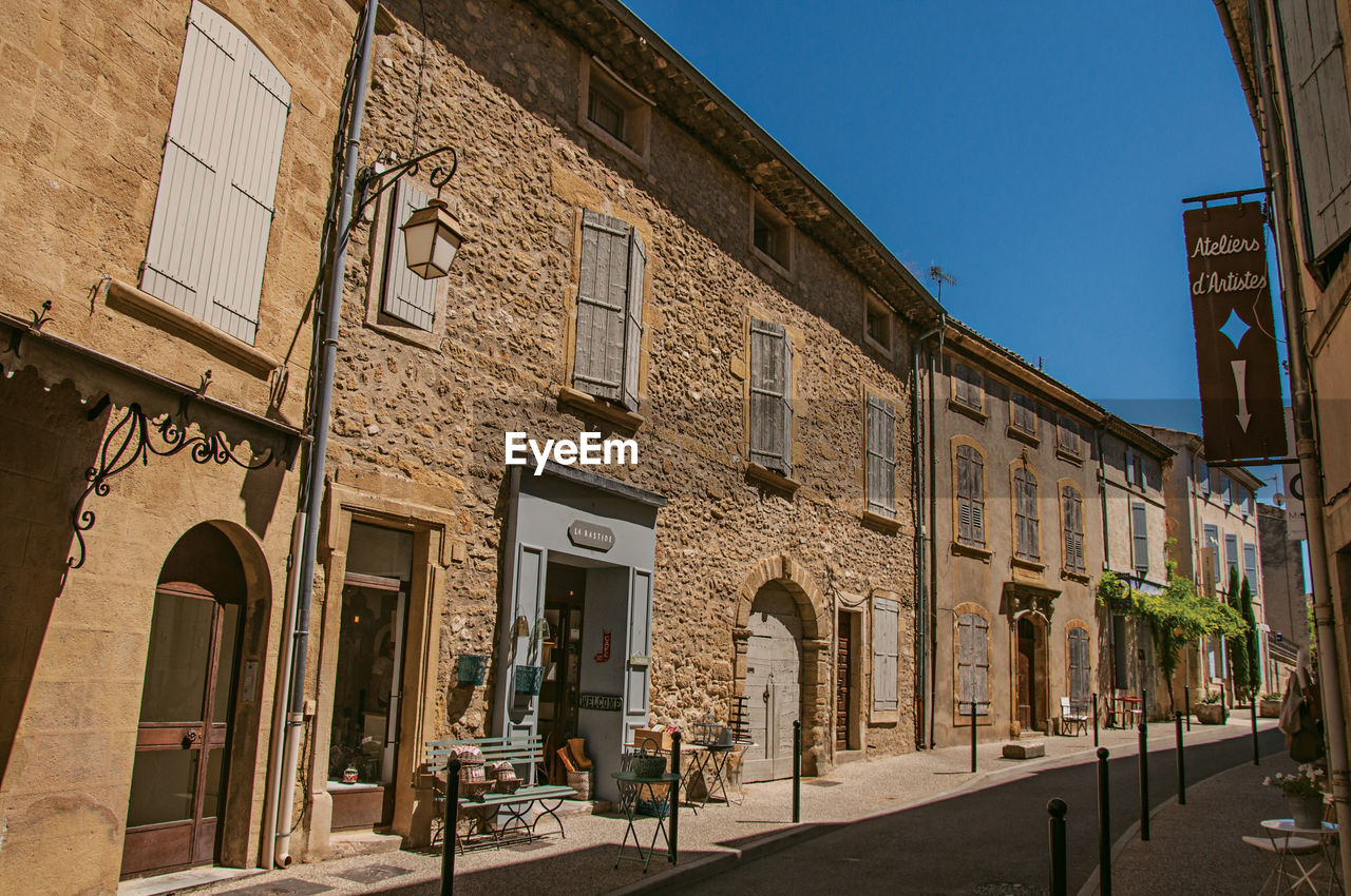 STREET BY BUILDINGS AGAINST SKY