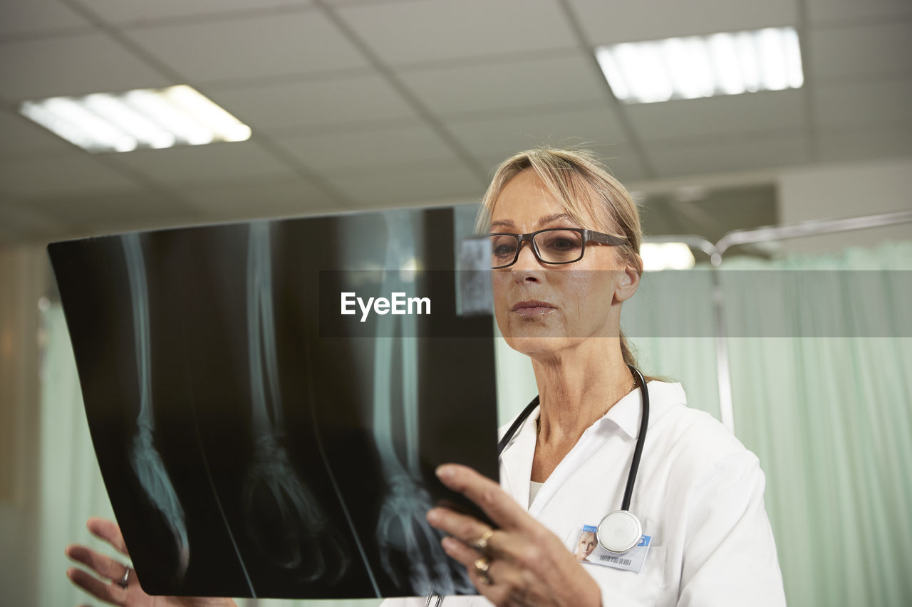 Female doctor with eyeglasses examining x-ray in medical room
