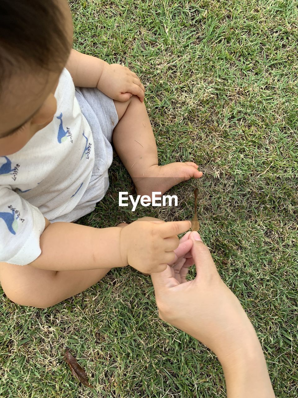 HIGH ANGLE VIEW OF BABY GIRL ON GRASSY FIELD