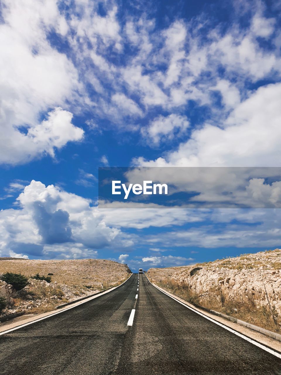 Surface level of empty road against cloudy sky