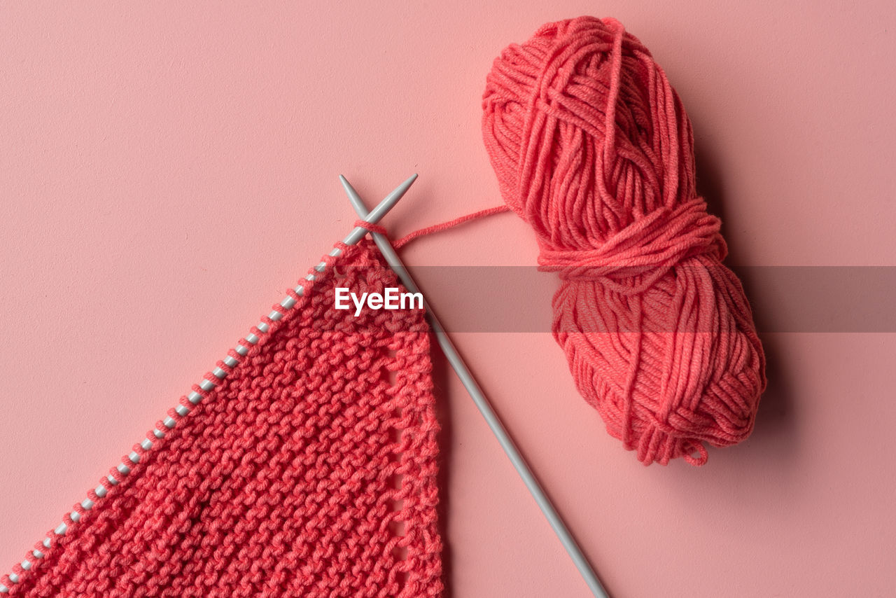 Directly above shot of knitting needle with crochet on colored background