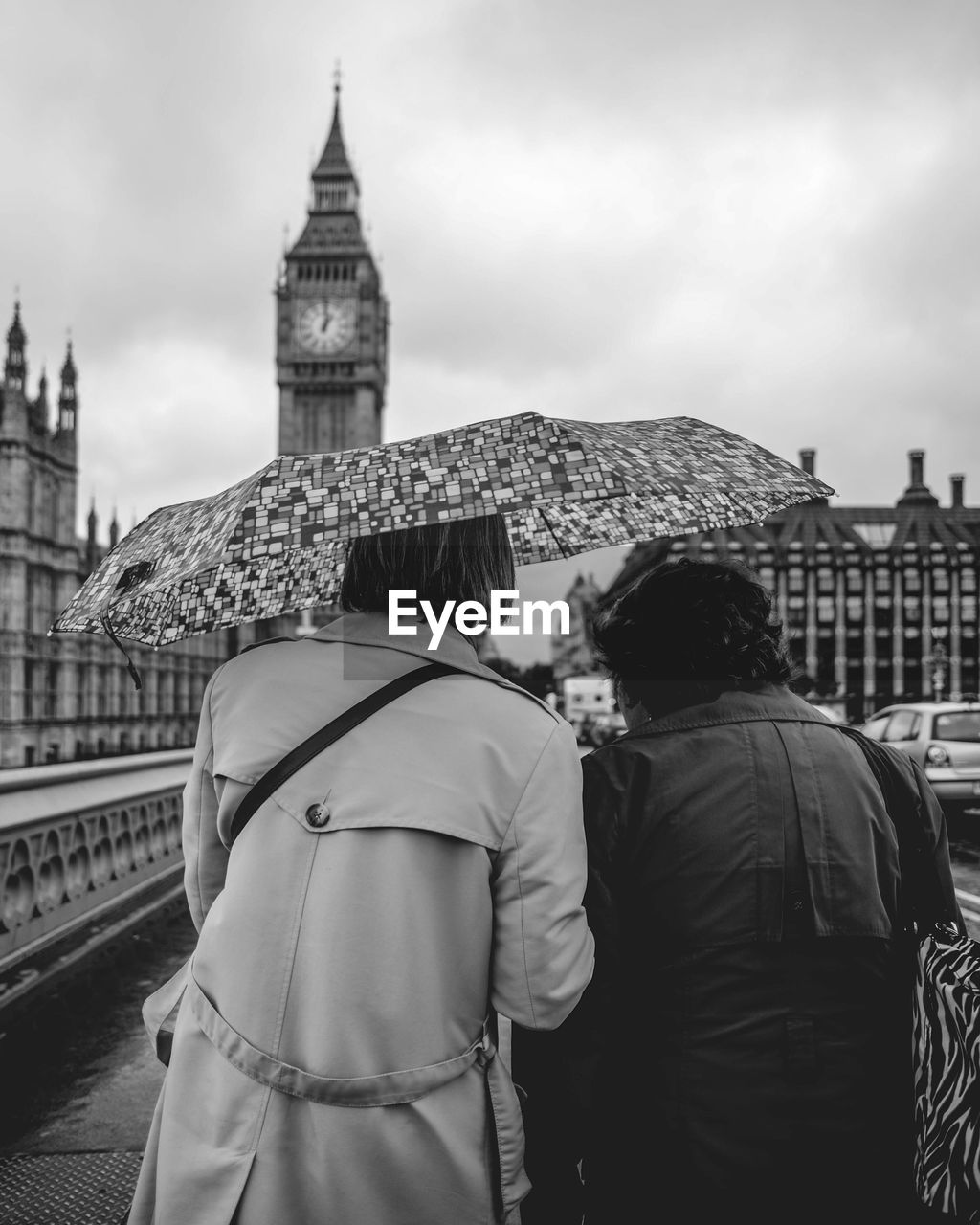 Rear view of people carrying umbrella while walking on street with big ben in background