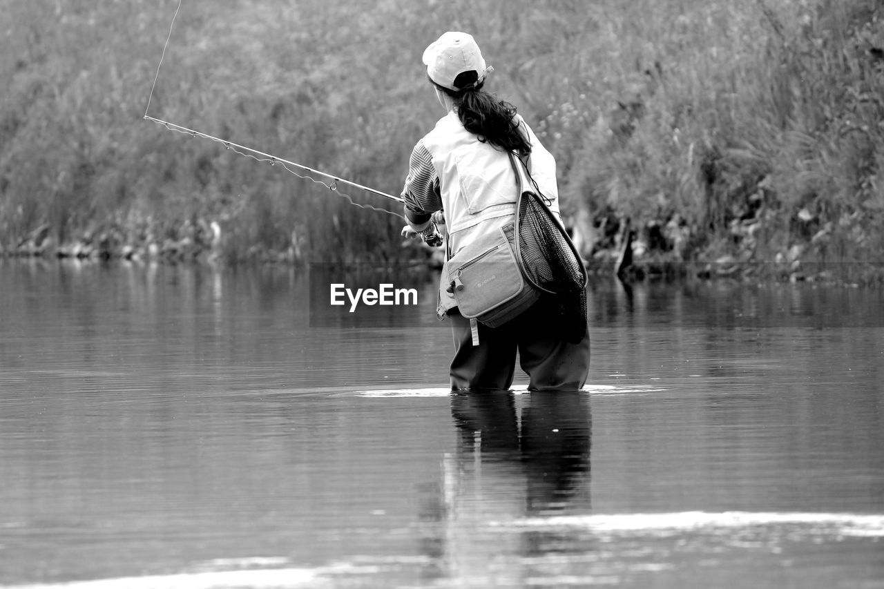 Rear view of woman fishing in river