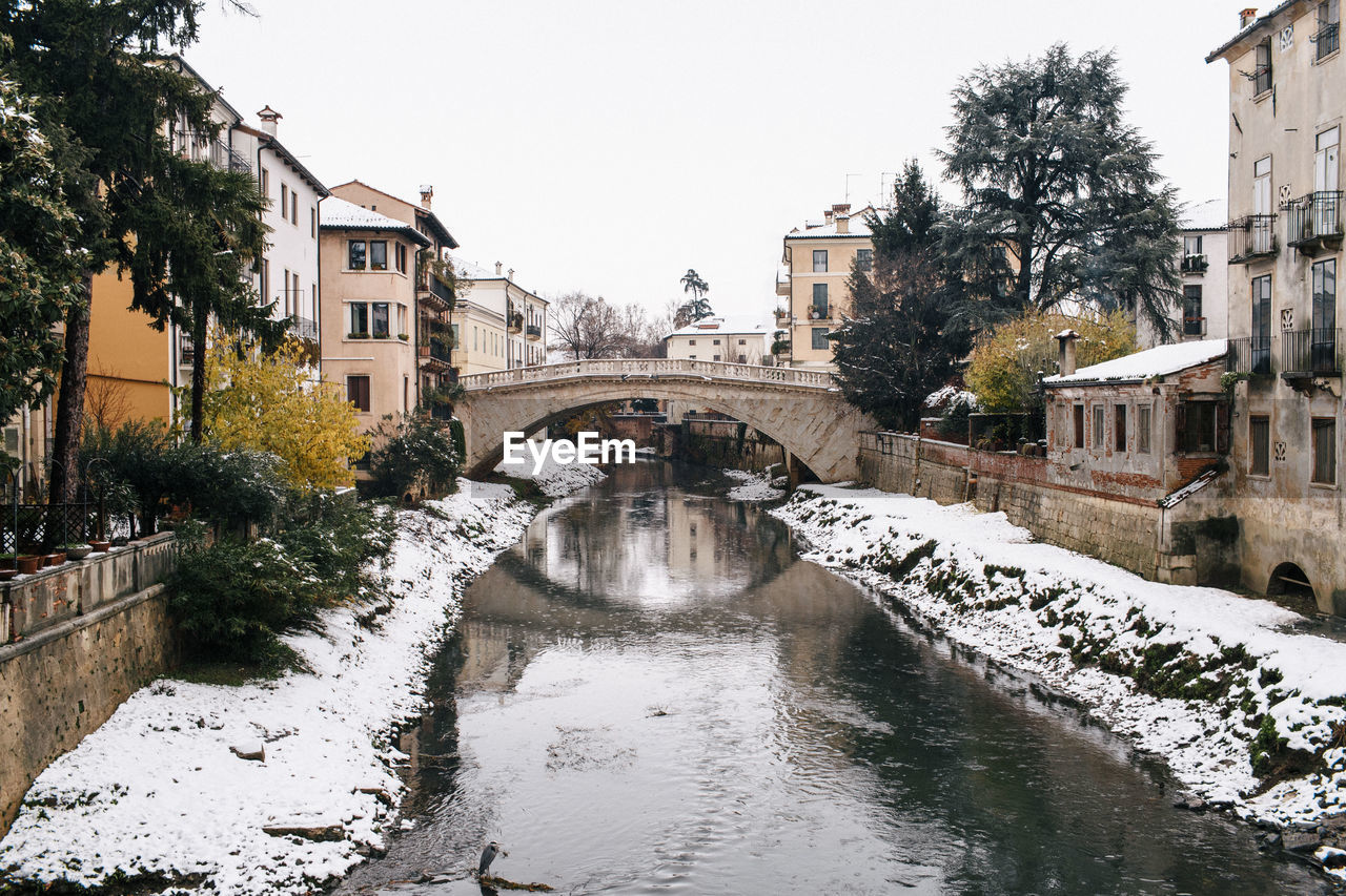 BRIDGE OVER RIVER AMIDST CITY AGAINST CLEAR SKY