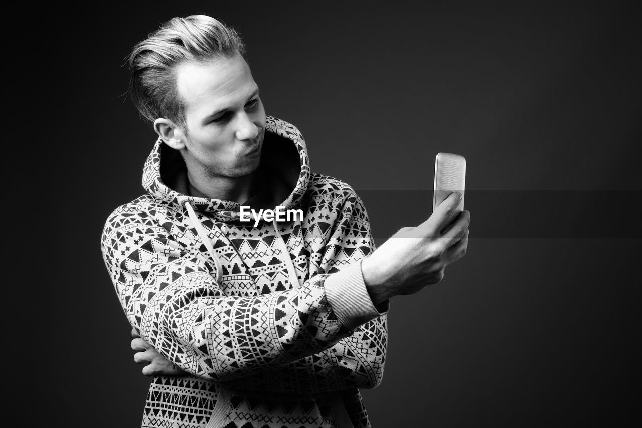 Man taking selfie against black background