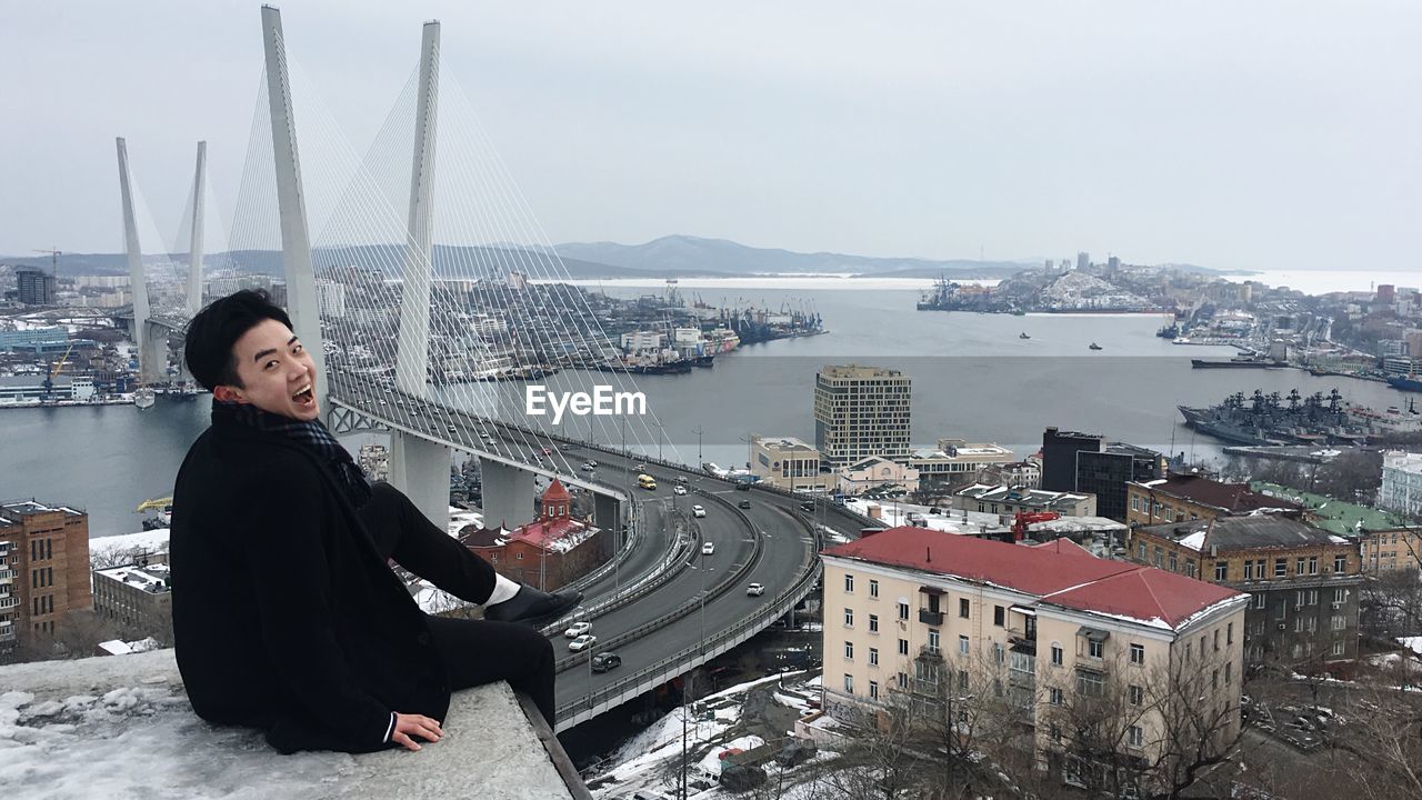 Portrait of young man screaming while sitting on building terrace in city