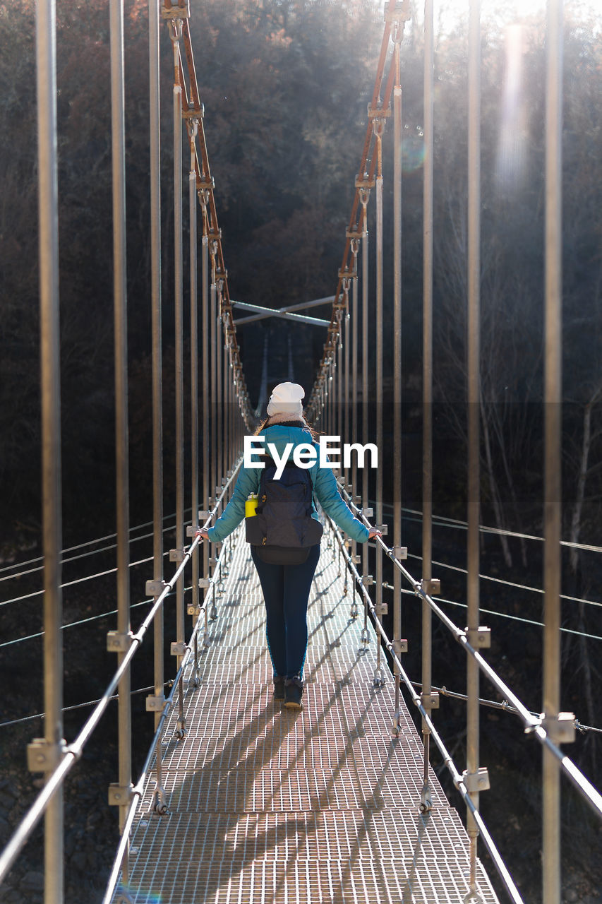 Rear view of woman walking on a suspension bridge sunshine day