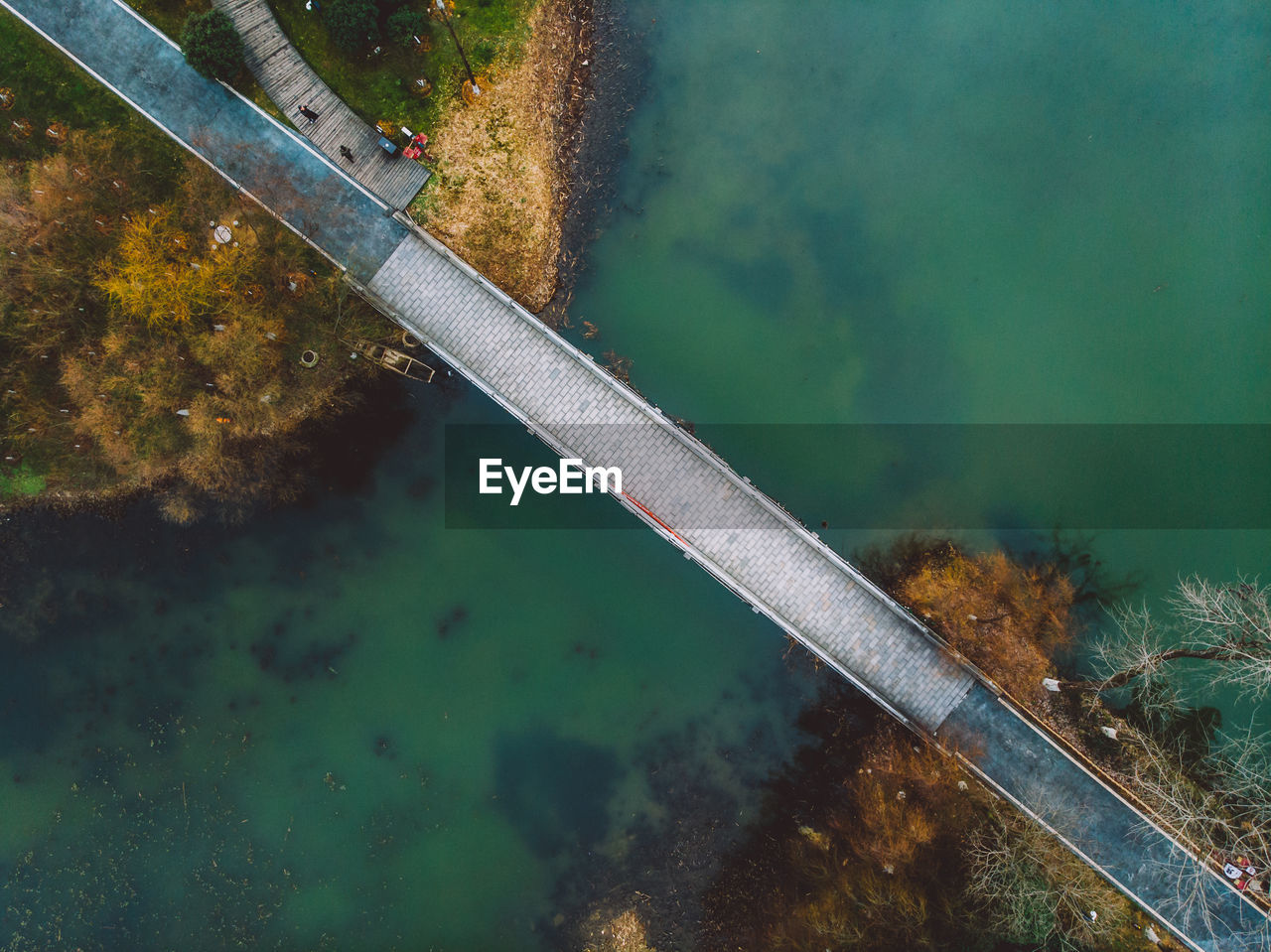 HIGH ANGLE VIEW OF BRIDGE OVER LAKE AGAINST PLANTS