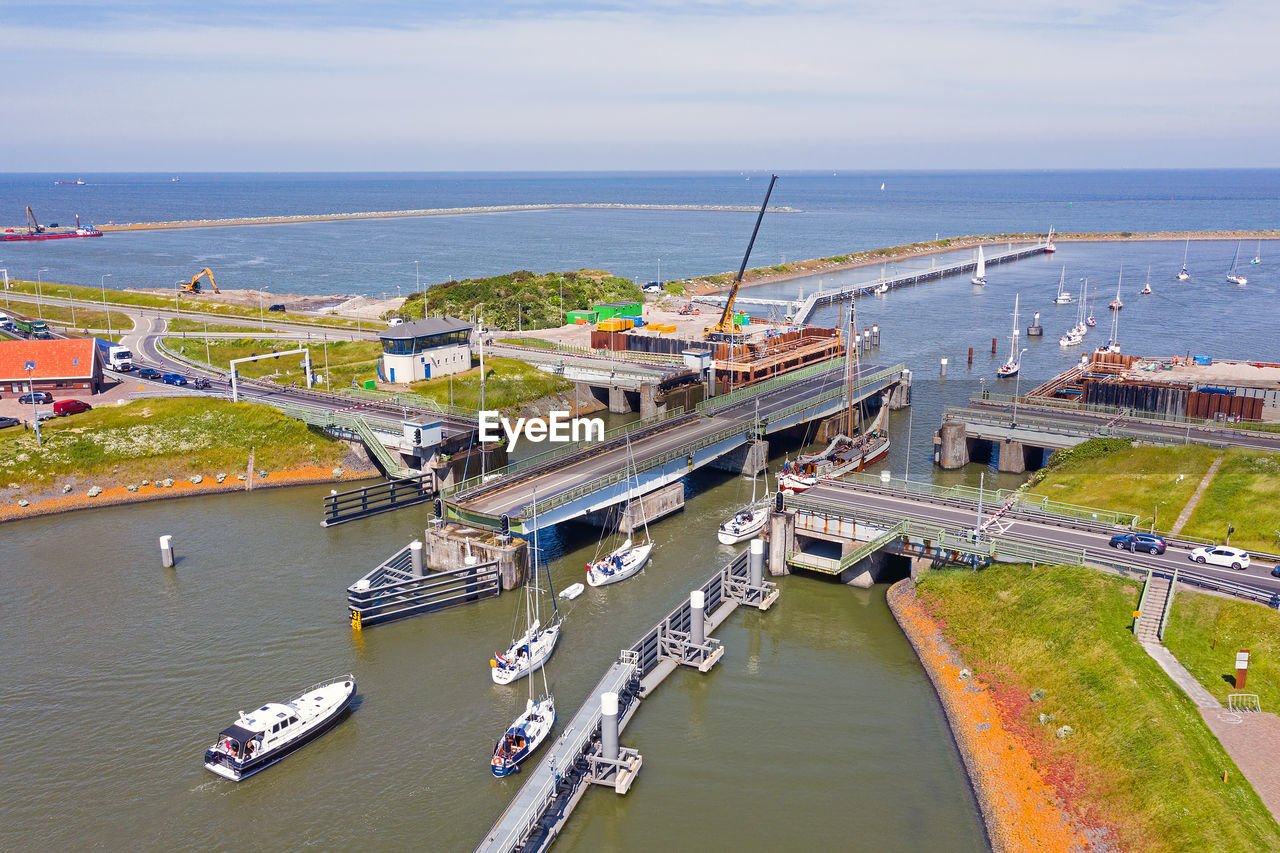 HIGH ANGLE VIEW OF ILLUMINATED PIER OVER SEA AGAINST SKY