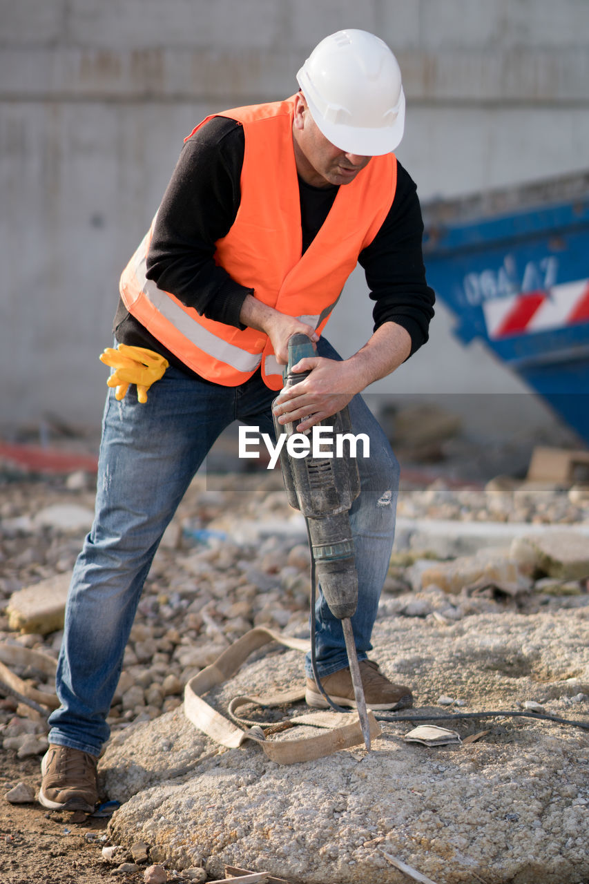 Construction worker drilling rock at site