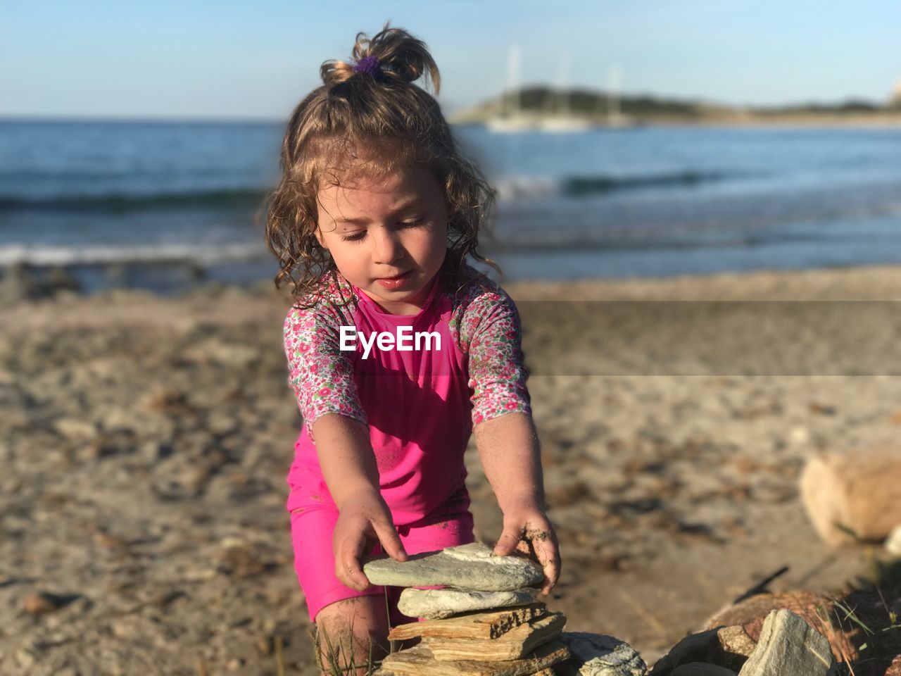 Close-up of girl stacking rocks at beach