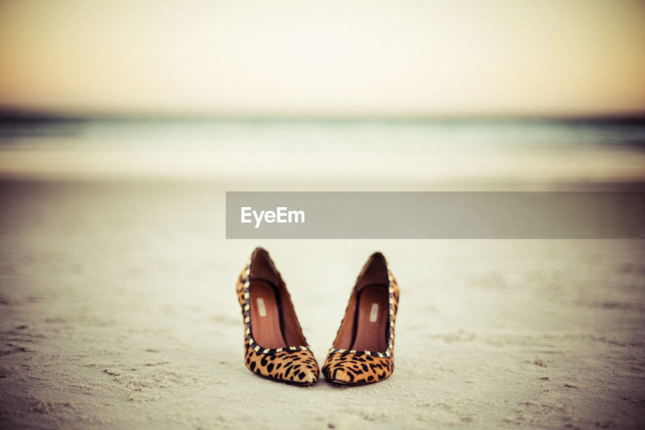 Close-up of shoes on beach