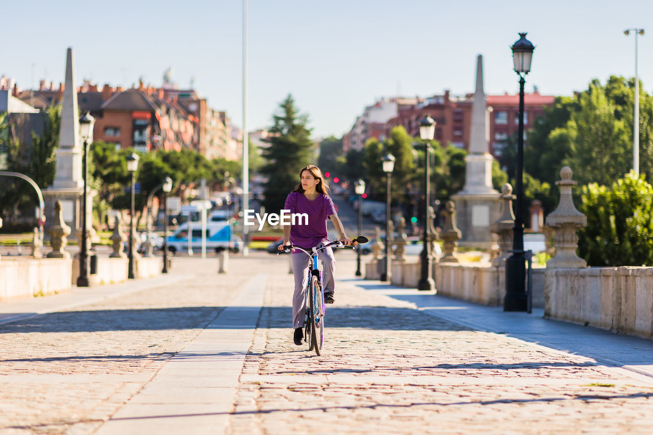 rear view of man riding bicycle on street in city