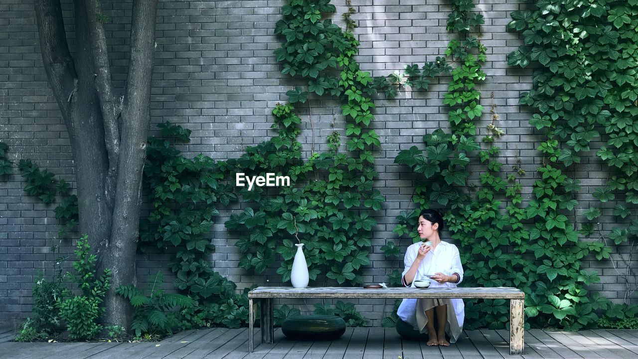 Portrait of smiling woman sitting against plants