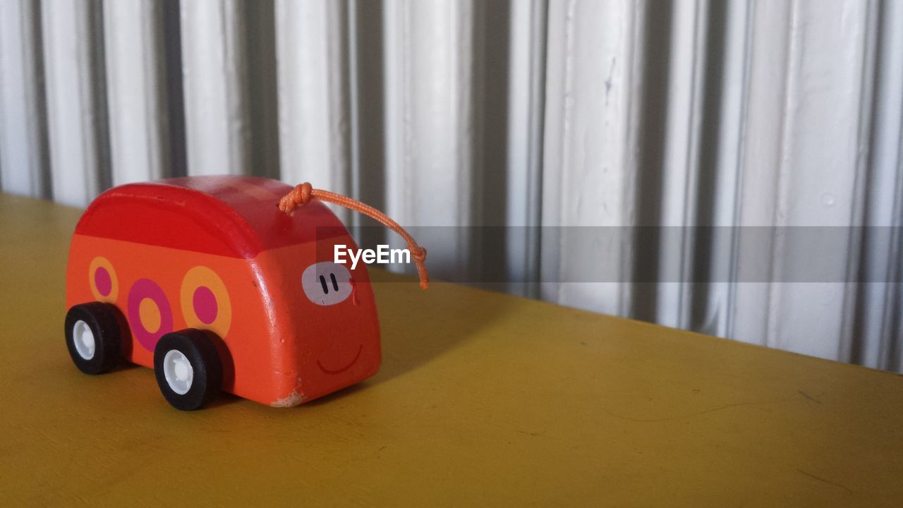 CLOSE-UP OF TOY CAR ON RED TABLE