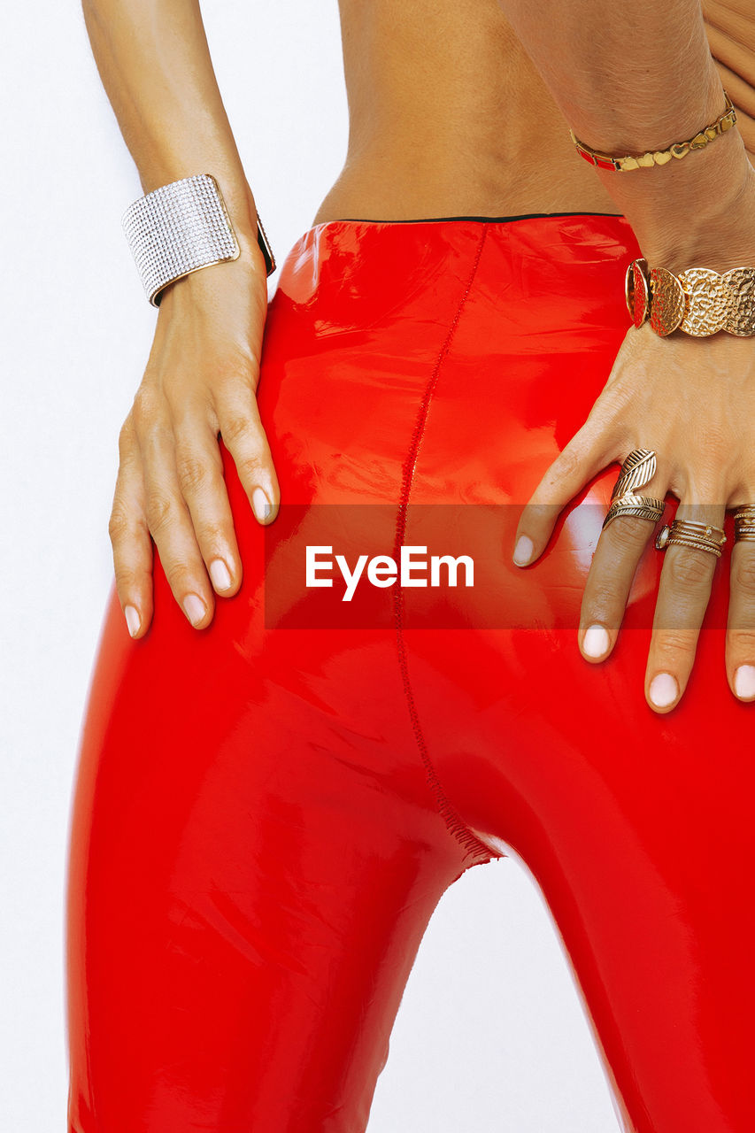 Unrecognizable model wearing red leather pants and trendy accessory jewelery. 
