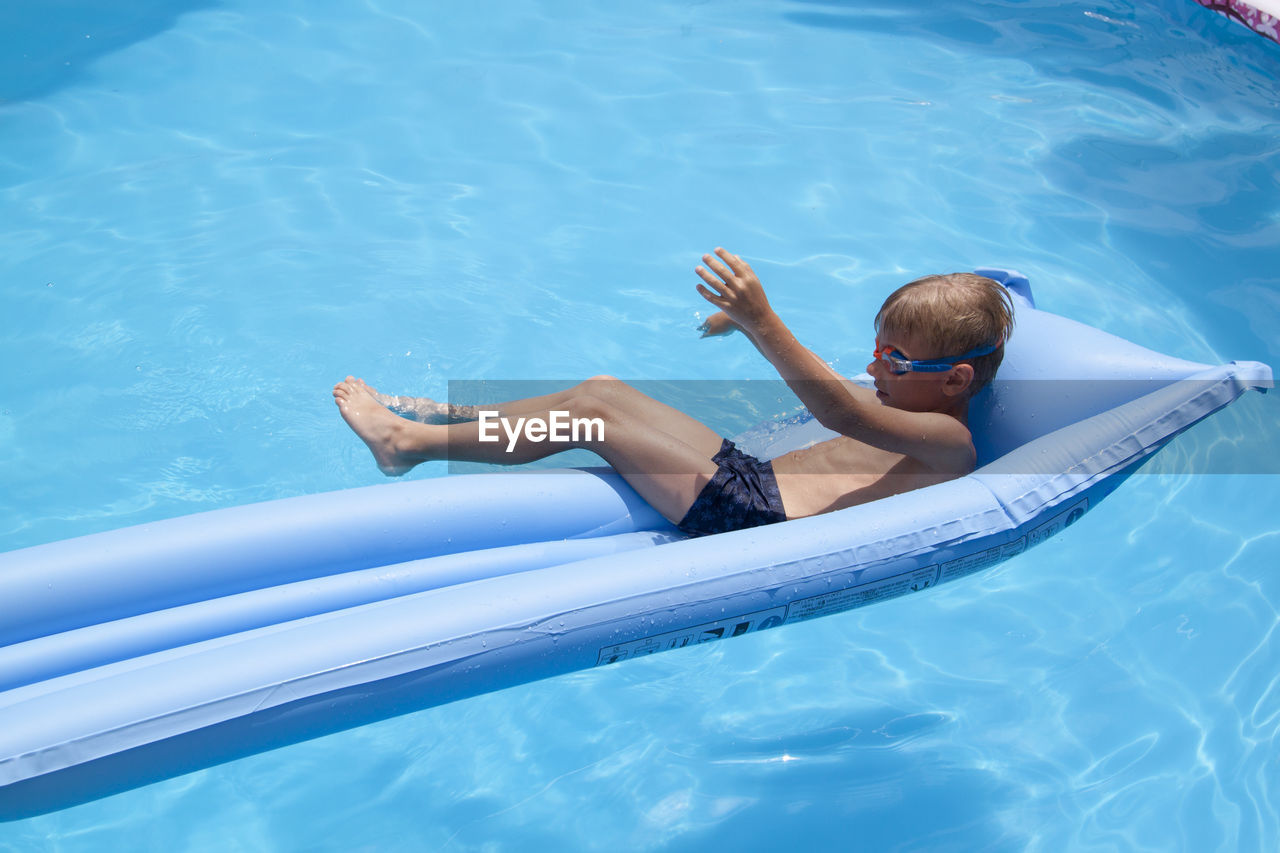 High angle view of boy relaxing in swimming pool