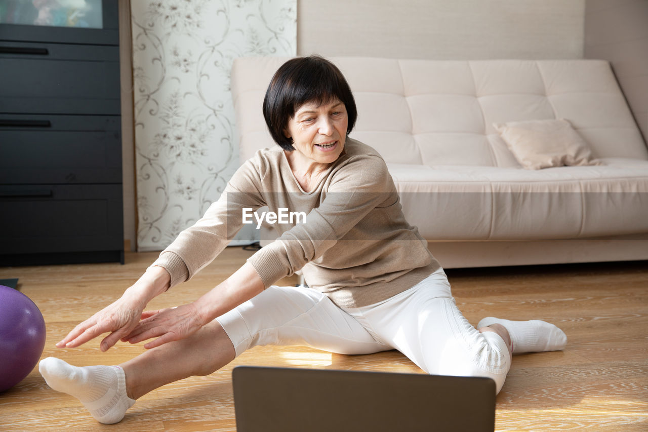 side view of young woman using laptop at home