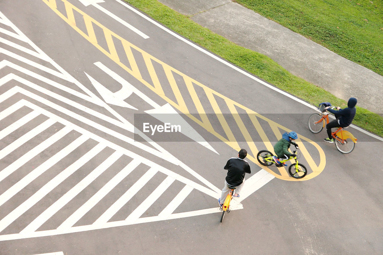 HIGH ANGLE VIEW OF MAN BICYCLING ON ROAD