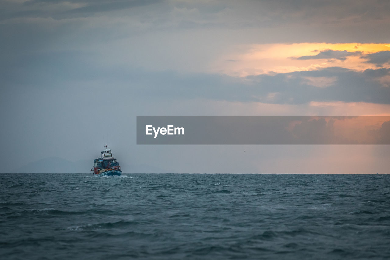 Boat sailing in sea against sky during sunset