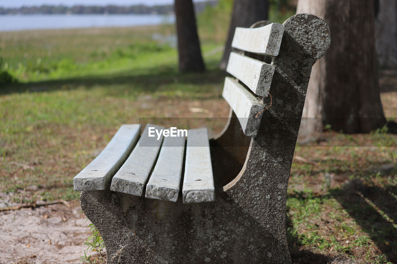 CLOSE-UP OF BENCH ON FIELD BY PARK