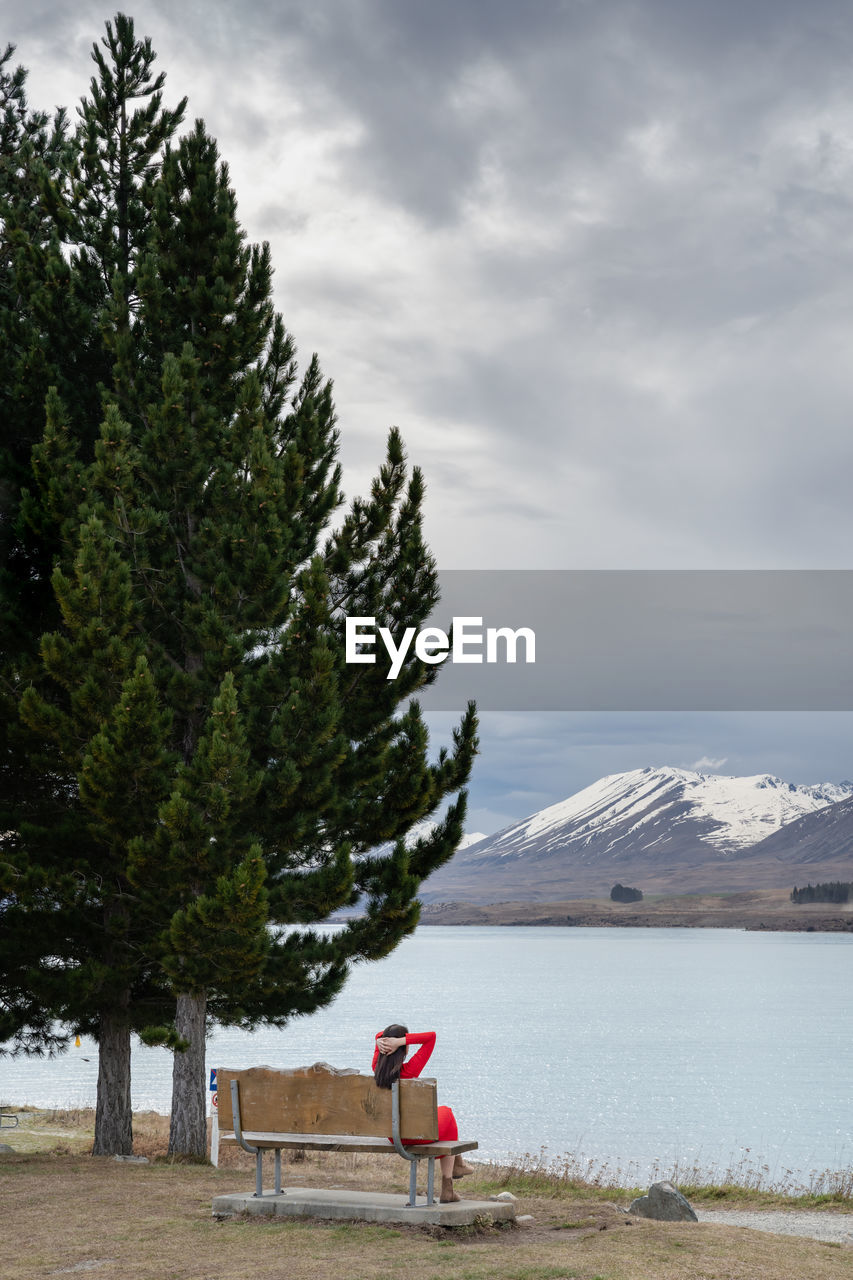 Asian female tourist pose at turquoise color lake tekapo with snowcapped mountain at the background