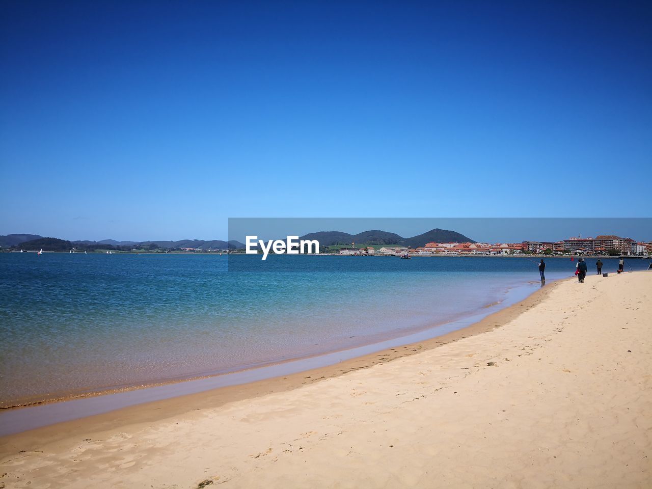 Scenic view of beach against clear blue sky