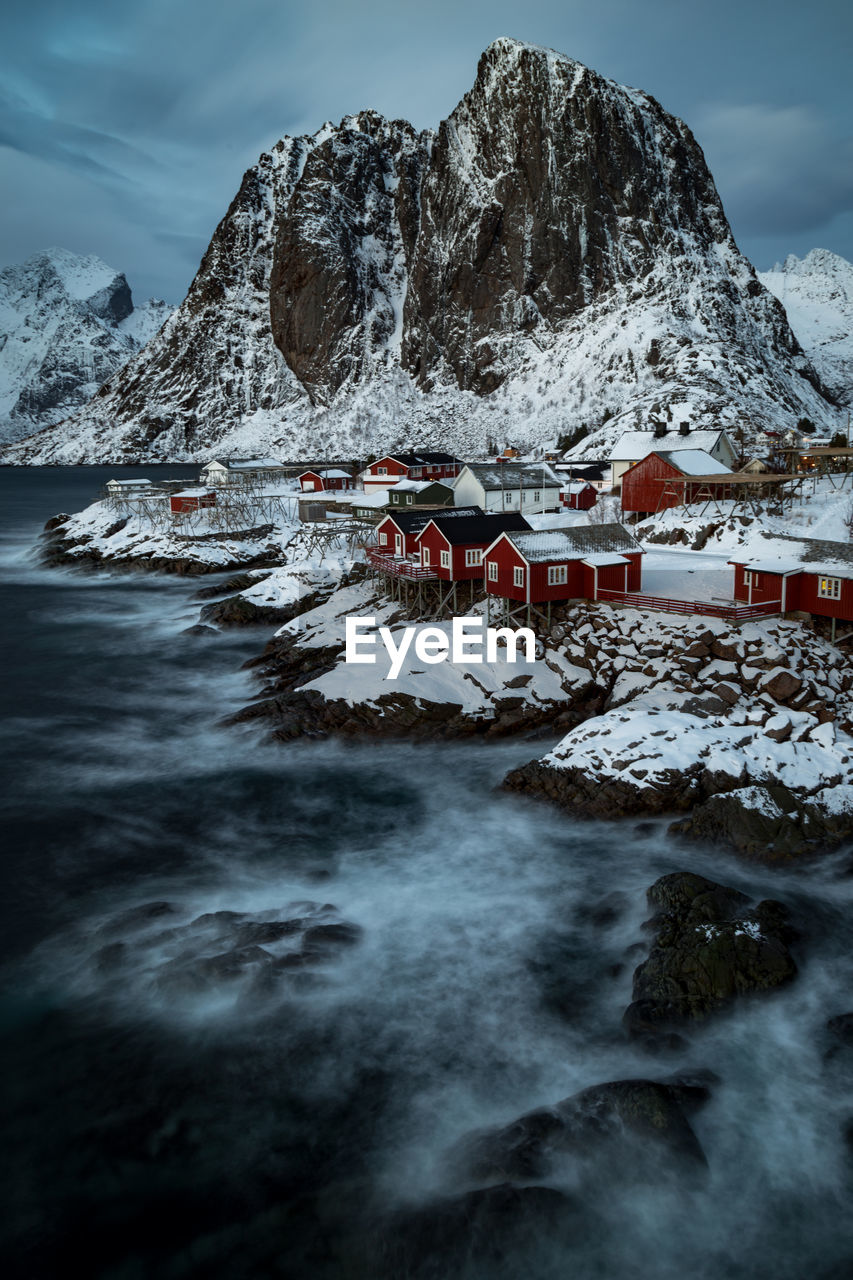 Aerial view of sea by town against mountain during winter