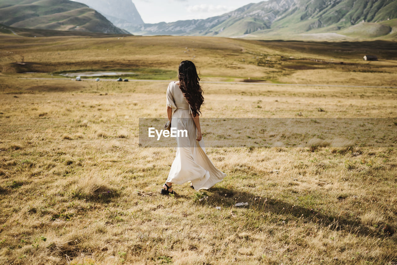 Young woman standing on field in the mountain landscape