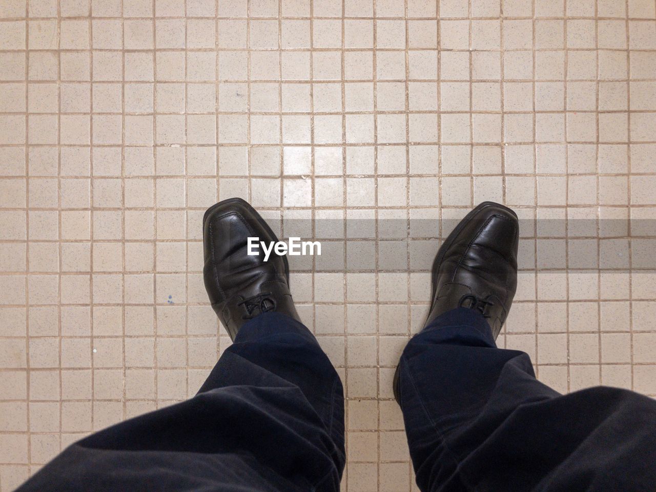 LOW SECTION OF MAN STANDING BY TILED FLOOR